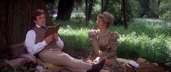Movie still from “Scrooge” (1970), directed by Ronald Neame – Two people sitting on the ground in a forest; Medium shot, Over the shoulder angle