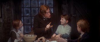 Movie still from “Scrooge” (1970), directed by Ronald Neame – A man and a boy sitting at a dinner table; Medium shot, Over the shoulder angle