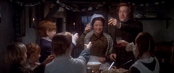 Movie still from “Scrooge” (1970), directed by Ronald Neame – A group of people sitting at a table with drinks; Medium shot, Low angle