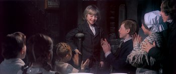 Movie still from “Scrooge” (1970), directed by Ronald Neame – A group of people clapping at an event; Medium shot, Over the shoulder angle