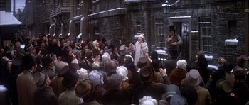 Movie still from “Scrooge” (1970), directed by Ronald Neame – A crowd of people sitting in front of a brick building; Wide shot, High angle