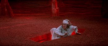 Movie still from “Scrooge” (1970), directed by Ronald Neame – A man in a white robe is laying in the dirt; Wide shot, High angle