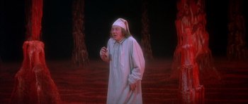 Movie still from “Scrooge” (1970), directed by Ronald Neame – A man dressed in a white robe and a white hat standing in front of trees; Medium shot, High angle