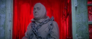 Movie still from “Scrooge” (1970), directed by Ronald Neame – A statue of a man with chains around his neck; Close Up shot, Low angle