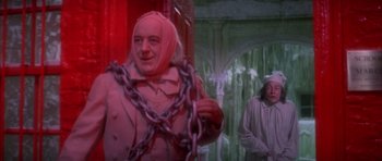 Movie still from “Scrooge” (1970), directed by Ronald Neame – A man chained up to a wall in a room with green walls; Medium shot, Low angle