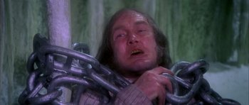 Movie still from “Scrooge” (1970), directed by Ronald Neame – A man with long hair is chained to a metal chain; Close Up shot, Low angle