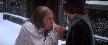 Movie still from “Scrooge” (1970), directed by Ronald Neame – An older man with long white hair and wearing a striped shirt; Close Up shot, Over the shoulder angle