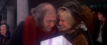 Movie still from “Scrooge” (1970), directed by Ronald Neame – An older man and a younger woman holding a present; Close Up shot, Over the shoulder angle
