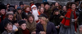 Movie still from “Scrooge” (1970), directed by Ronald Neame – A group of people gathered around a man in a santa claus suit; Medium shot, High angle