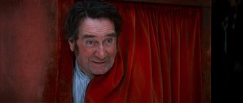 Movie still from “Scrooge” (1970), directed by Ronald Neame – A person behind a red curtain; Close Up shot, Low angle