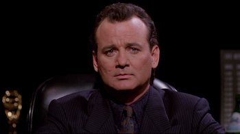 Movie still from “Scrooged” (1988), directed by Richard Donner – A person wearing a suit and tie; Close Up shot, Over the shoulder angle