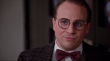 Movie still from “Scrooged” (1988), directed by Richard Donner – A person wearing glasses and a bow tie; Close Up shot, Over the shoulder angle