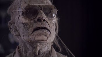 Movie still from “Scrooged” (1988), directed by Richard Donner – A person wearing a mask and sunglasses; Close Up shot, Low angle