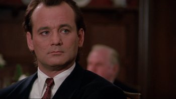 Movie still from “Scrooged” (1988), directed by Richard Donner – A man wearing a suit and tie sitting in front of a judge; Close Up shot, Low angle