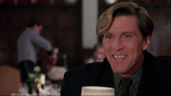 Movie still from “Scrooged” (1988), directed by Richard Donner – A person sitting at a table with a drink; Close Up shot, Low angle