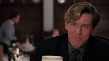 Movie still from “Scrooged” (1988), directed by Richard Donner – A person sitting at a table with a drink; Close Up shot, Over the shoulder angle