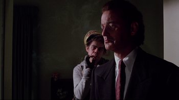 Movie still from “Scrooged” (1988), directed by Richard Donner – A man in a suit and tie next to another man in a suit and tie; Medium shot, Over the shoulder angle