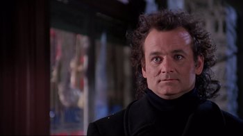 Movie still from “Scrooged” (1988), directed by Richard Donner – A man in a black jacket is looking at the camera; Close Up shot, Low angle