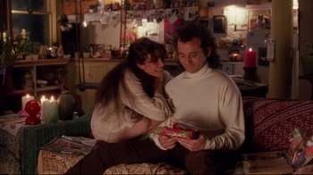 Movie still from “Scrooged” (1988), directed by Richard Donner – A man and a woman sitting on a bed holding a present; Medium shot, Over the shoulder angle