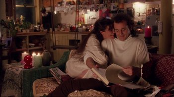 Movie still from “Scrooged” (1988), directed by Richard Donner – A man and a woman sitting on a bed reading a book; Medium shot, Low angle