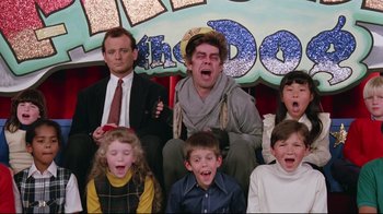 Movie still from “Scrooged” (1988), directed by Richard Donner – A group of kids and a man sitting in front of a sign; Wide shot, Low angle