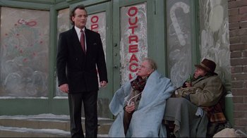 Movie still from “Scrooged” (1988), directed by Richard Donner – A man standing next to an older man in front of a building; Wide shot, Low angle