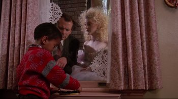 Movie still from “Scrooged” (1988), directed by Richard Donner – A man and a woman sitting in front of a boy; Medium shot, Low angle