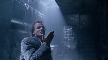 Movie still from “Scrooged” (1988), directed by Richard Donner – A man standing in the middle of a room with his hands clasped together; Medium shot, Low angle