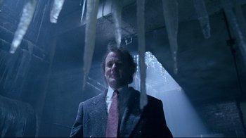 Movie still from “Scrooged” (1988), directed by Richard Donner – A man in a suit and tie standing next to icicles; Medium shot, Low angle