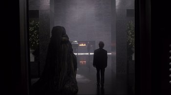 Movie still from “Scrooged” (1988), directed by Richard Donner – A man in a suit standing in front of a fireplace; Wide shot, Over the shoulder angle