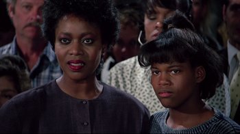Movie still from “Scrooged” (1988), directed by Richard Donner – Two women and a boy are standing in a crowd; Close Up shot, Over the shoulder angle