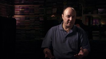 Movie still from “Searching for Sugar Man” (2012), directed by Malik Bendjelloul – A man in a blue shirt is sitting in a room; Close Up shot, Low angle