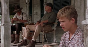 Movie still from “Secondhand Lions” (2003), directed by Tim McCanlies – A man sitting in a rocking chair on a porch with two other men; Medium shot, Low angle