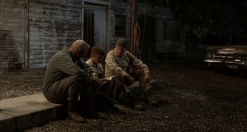 Movie still from “Secondhand Lions” (2003), directed by Tim McCanlies – A group of men sitting next to each other on the ground; Wide shot, Over the shoulder angle