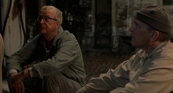 Movie still from “Secondhand Lions” (2003), directed by Tim McCanlies – A man sitting next to another man on a ground; Medium shot, Over the shoulder angle