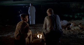 Movie still from “Secondhand Lions” (2003), directed by Tim McCanlies – A man and a boy sitting in front of a fire at night; Wide shot, Over the shoulder angle