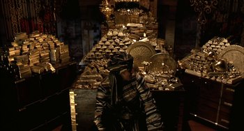 Movie still from “Secondhand Lions” (2003), directed by Tim McCanlies – A man sitting in front of a table filled with gold; Medium shot, High angle