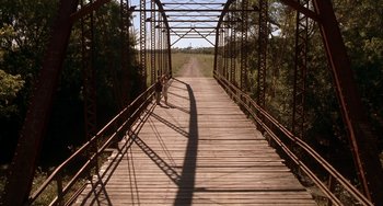 Movie still from “Secondhand Lions” (2003), directed by Tim McCanlies – A person is standing on a bridge over a dirt road; Extreme Wide shot, High angle
