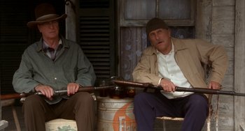 Movie still from “Secondhand Lions” (2003), directed by Tim McCanlies – A couple of men sitting next to each other holding guns; Medium shot, Low angle
