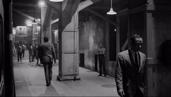 Movie still from “Seconds” (1966), directed by John Frankenheimer – A black and white photo of men in suits walking in an alley; Wide shot, High angle