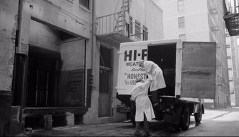Movie still from “Seconds” (1966), directed by John Frankenheimer – An old photo of a woman standing next to a meat truck; Wide shot, Low angle