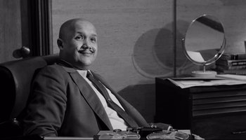 Movie still from “Seconds” (1966), directed by John Frankenheimer – A man sitting at a desk in front of a mirror; Medium shot, Low angle