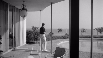 Movie still from “Seconds” (1966), directed by John Frankenheimer – A black and white photo of a man standing outside; Wide shot, Low angle