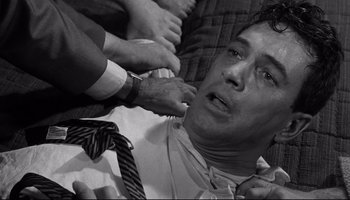 Movie still from “Seconds” (1966), directed by John Frankenheimer – A black - and - white photo of a man getting dressed; Close Up shot, High angle