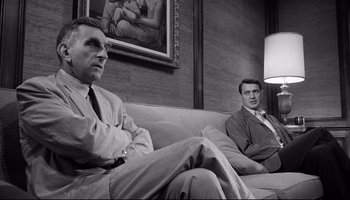 Movie still from “Seconds” (1966), directed by John Frankenheimer – Two men sitting on a couch in front of a painting; Medium shot, Low angle