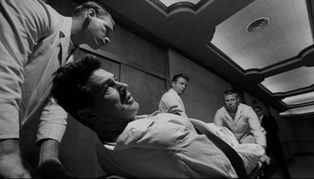 Movie still from “Seconds” (1966), directed by John Frankenheimer – A group of young men sitting in a room together; Medium shot, Low angle