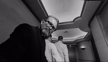 Movie still from “Seconds” (1966), directed by John Frankenheimer – A man in a suit and tie standing in front of another man; Medium shot, Low angle