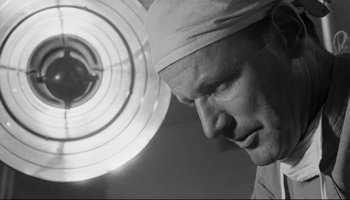 Movie still from “Seconds” (1966), directed by John Frankenheimer – A black - and - white photo of a man wearing a surgical cap; Close Up shot, Low angle