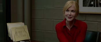 Movie still from “Secret in Their Eyes” (2015), directed by Billy Ray – A woman in a red shirt sitting in front of a brick wall; Close Up shot, Over the shoulder angle