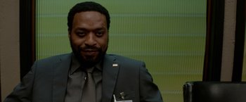 Movie still from “Secret in Their Eyes” (2015), directed by Billy Ray – A man wearing a suit and tie in front of a green wall; Close Up shot, Over the shoulder angle